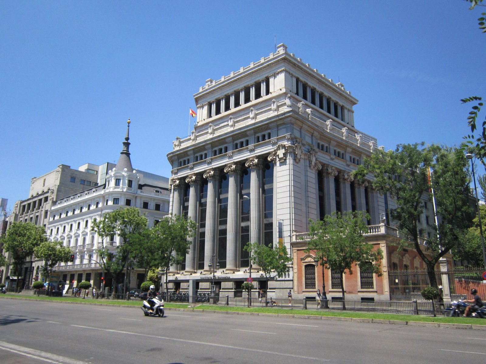 Grand buildings line a sunny street in Madrid, Spain, symbolizing urban elegance.